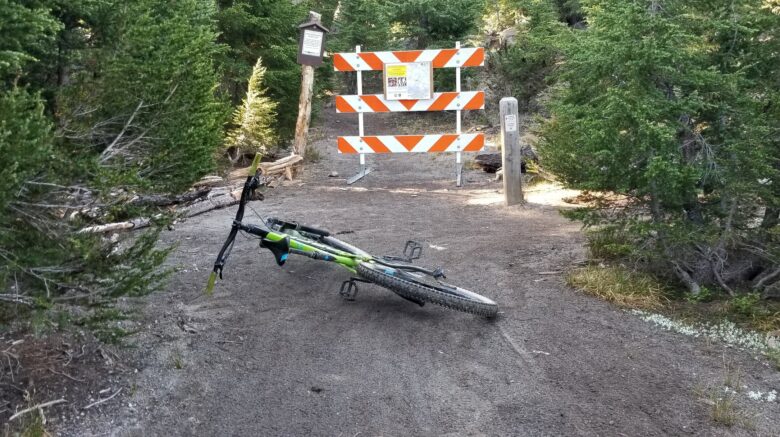 trail closure sign with bike lying down on trail in front
